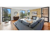 Bright living room features a stone fireplace, hardwood floors, and large windows with scenic outdoor views at 1111 Race St # 6B, Denver, CO 80206
