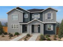 Charming two-story home showcasing gray and blue siding, white trim, and a well-manicured front yard at 2234 Farmlore Dr, Brighton, CO 80601