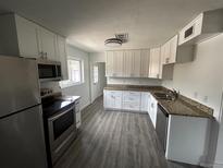 Bright kitchen features stainless appliances, granite counters, white cabinets, and wood flooring at 1550 Eppinger Blvd, Thornton, CO 80229