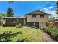 Charming two-story home with a brick facade, complemented by a well-manicured lawn and lush greenery at 8346 W Woodard Dr, Lakewood, CO 80227