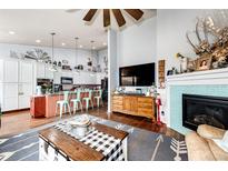 Open-concept living room featuring a tile fireplace, ceiling fan, and open view to the kitchen at 11699 Pink Phlox Dr, Parker, CO 80134