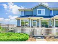 Charming blue townhome with white picket fence, lush green bush, and well-maintained landscaping at 9102 W 107Th Pl, Broomfield, CO 80021