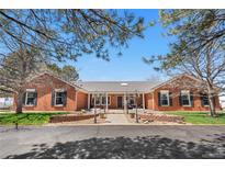 Stunning red brick home with symmetrical design and mature trees providing shade and curb appeal at 97 S Coolidge St, Aurora, CO 80018