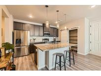 Modern kitchen features stainless steel appliances, a center island with seating, and pendant lighting at 6153 N Ceylon St # 303, Denver, CO 80249