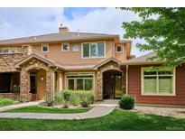 Inviting two-story townhome with stone accents, manicured lawn and front yard landscaping at 8638 Gold Peak Dr # D, Highlands Ranch, CO 80130