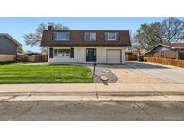 Charming two-story home with a well-manicured lawn, blue door and shutters, and an attached garage at 5203 Scranton St, Denver, CO 80239