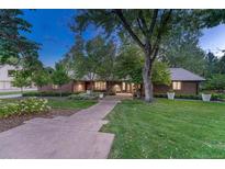 Charming brick home with manicured lawn, mature trees, and inviting walkway at 5795 Oak Creek Ln, Greenwood Village, CO 80121
