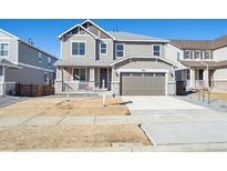 Two-story home showcasing a well-manicured lawn, a two-car garage, and a welcoming front porch at 660 Split Rock Dr, Erie, CO 80516