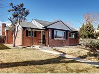 Charming brick home with a well-maintained lawn and mature trees under a clear blue sky at 3033 Leyden St, Denver, CO 80207