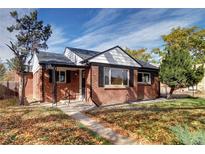 Charming brick home featuring a well-maintained front yard with mature trees and a cozy covered porch at 3033 Leyden St, Denver, CO 80207