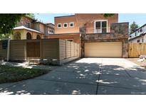 Contemporary home featuring a modern fence, neutral stucco, stone accents, and a two-car garage at 467 Harrison St, Denver, CO 80206