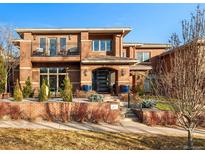 Striking two-story brick home with black iron gate, balcony, mature trees and meticulously manicured landscaping at 418 Steele St, Denver, CO 80206