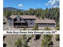 Stunning mountain home featuring a spacious deck and views of a lush, tree-filled landscape at 32091 Black Widow Dr, Conifer, CO 80433