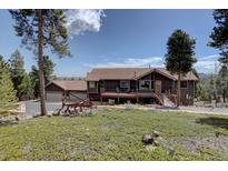 Charming brown home featuring a deck and three-car garage, nestled on a scenic lot with mature trees at 32091 Black Widow Dr, Conifer, CO 80433