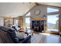 Comfortable living room featuring a stone fireplace, with views and vaulted ceilings at 32091 Black Widow Dr, Conifer, CO 80433