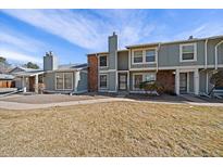 Inviting townhouse featuring a stone accent wall, blue siding, and a well-manicured lawn at 10235 E Evans Ave # 104, Aurora, CO 80247