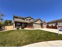 Inviting two-story home with a three-car garage, a well-manicured lawn, and beautiful landscaping at 11895 Hitching Post Ct, Parker, CO 80134