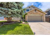 Charming home with a stone facade, attached garage, and a well-maintained front yard with mature tree at 7166 Newhall Dr, Highlands Ranch, CO 80130