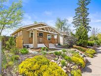 Charming bungalow featuring a landscaped front yard with lush flowers and a cozy front porch at 1987 S Downing St, Denver, CO 80210