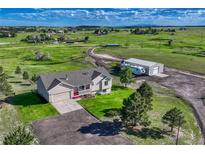 Expansive aerial view of a home on acreage with a large garage or workshop building and mature trees at 1166 Belgian Trl, Elizabeth, CO 80107