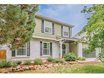 Charming two-story home featuring a white brick facade, green siding, black shutters, and a well-manicured front yard at 16051 E Alabama Dr, Aurora, CO 80017