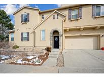 Tan two-story home with a two-car garage and landscaping at 10587 Parkington Ln # B, Highlands Ranch, CO 80126