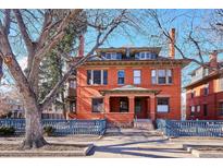 Charming brick home featuring symmetrical design, covered porch, and a blue fence at 1401 N Franklin St # 1, Denver, CO 80218