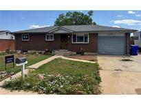 Charming single-story brick home with a tidy yard and driveway leading to a one-car garage at 8250 Ralph Ln, Denver, CO 80221