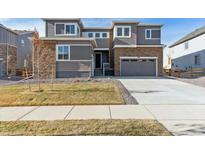 Two-story home with gray siding, stone accents, and a two-car garage at 1749 Marlowe E Cir, Erie, CO 80516