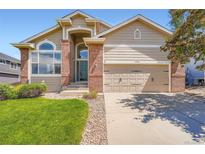 Charming home features a well-manicured lawn, brick accents, and an attached two-car garage at 22436 E Maplewood Pl, Aurora, CO 80015