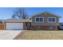 Charming home showcasing a well-maintained lawn, brick accents, and an attached two-car garage at 1923 S Cody Way, Lakewood, CO 80227