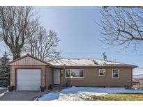 Ranch style home with attached garage, landscaping, and snow covered yard at 5421 S Sherman St, Littleton, CO 80121