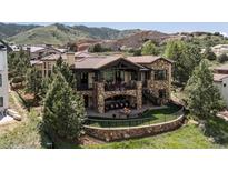 Stunning stone home with a tile roof, outdoor patio and landscaped backyard in a mountain setting at 7188 Raphael Ln, Littleton, CO 80125