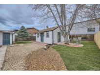 Cozy home featuring a gravel driveway, well-maintained lawn, and an inviting outdoor seating area at 3379 S Eliot St, Englewood, CO 80110