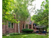 Charming brick home with manicured lawn, mature trees, and outdoor seating area at 2409 E Cedar Ave, Denver, CO 80209