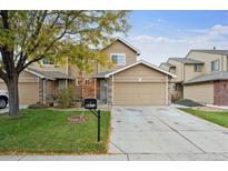 Tan two-story townhome with attached garage and well-manicured lawn at 9673 Ironton St, Commerce City, CO 80022