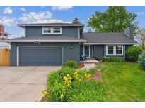 Charming home featuring a well-manicured lawn and a gray two-car garage for ample parking and storage space at 6537 S Brentwood Way, Littleton, CO 80123