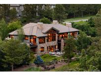 Expansive stone house featuring large windows and outdoor seating, nestled among lush trees at 786 International Isle Dr, Castle Rock, CO 80108