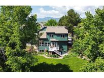 Lovely two-story home with a well-maintained lawn, mature trees, and a deck, creating a serene backyard retreat at 8296 S Reed St, Littleton, CO 80128