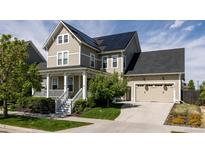 Charming two-story home with a covered porch, well-maintained lawn, and solar panels on the roof at 6072 Chester St, Denver, CO 80238