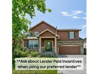 Charming two-story home featuring wood siding, stone accents, and a well-maintained front lawn and attached two-car garage at 9919 Memphis St, Commerce City, CO 80022