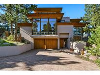 Contemporary home with a brick driveway, large windows, and a wooden garage door at 9041 Eastridge Rd, Golden, CO 80403
