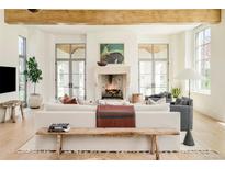 Bright living room boasts a stone fireplace, high ceilings with wooden beams, and lots of natural light at 20 Viking Dr, Cherry Hills Village, CO 80113