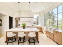 Spacious kitchen with eat-in island, stone counters and backsplash, and pendant lighting at 20 Viking Dr, Cherry Hills Village, CO 80113