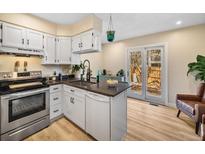 Bright kitchen features white cabinets, stainless steel appliances, and access to a private patio at 1247 S Idalia St, Aurora, CO 80017