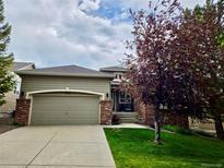 Charming single-Gathering home features a two-car garage, brick accents, and a well-manicured front lawn at 1033 Bramblewood Dr, Castle Pines, CO 80108