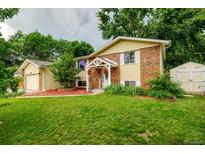 Charming two-story home with a well-manicured lawn, brick accents, and welcoming front porch at 8217 Club Crest Dr, Arvada, CO 80005