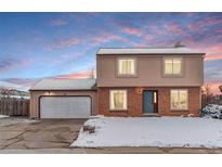 Two-story home with brick and stucco exterior, attached garage, snow-covered yard and lovely sky at 1206 Baldwin Park Cir, Castle Rock, CO 80104