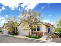 Charming home featuring a two-car garage, stone accents, and beautiful landscaping under a partly cloudy sky at 6617 S Reed Way # C, Littleton, CO 80123