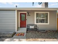 Charming home entrance featuring a red door, stone chimney, and a cozy bench at 2910 S Racine St, Aurora, CO 80014